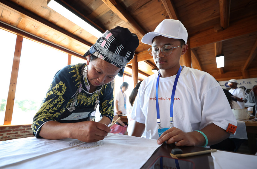 7月21日，手工藝人向留學生示范苗族蠟染繪畫技藝。