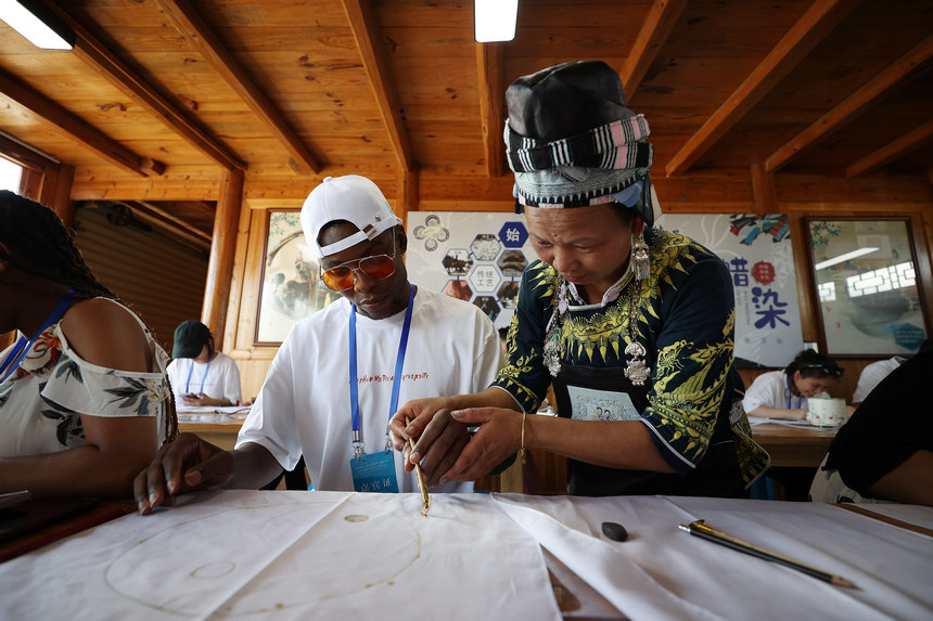 7月21日，手工藝人在指導留學生學習苗族蠟染繪畫。