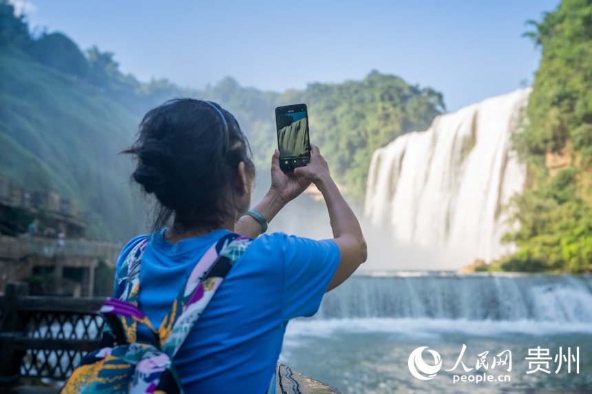 游客在黃果樹大瀑布前拍照。人民網 涂敏攝