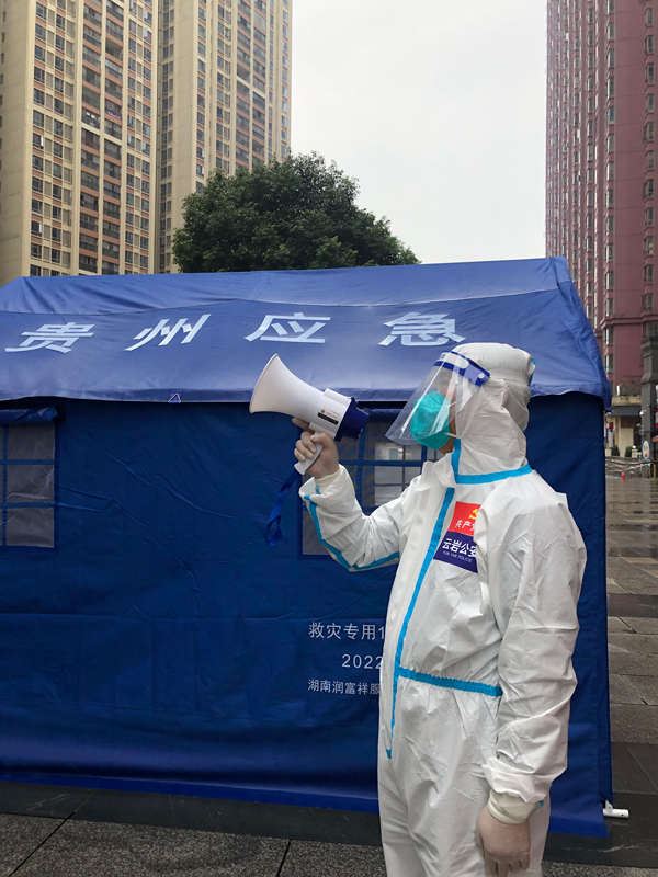李剛在執勤點用喇叭向樓上居民進行防疫提示。貴陽市公安局云巖分局供圖