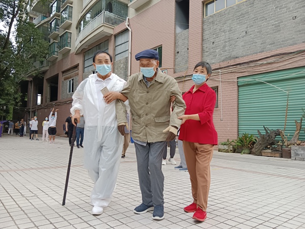 5 圖為陳進敏攙扶腳腿不便鄰居采集核酸（左一）。