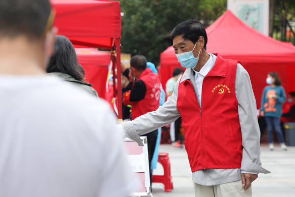 志愿者引導(dǎo)居民有序排隊。