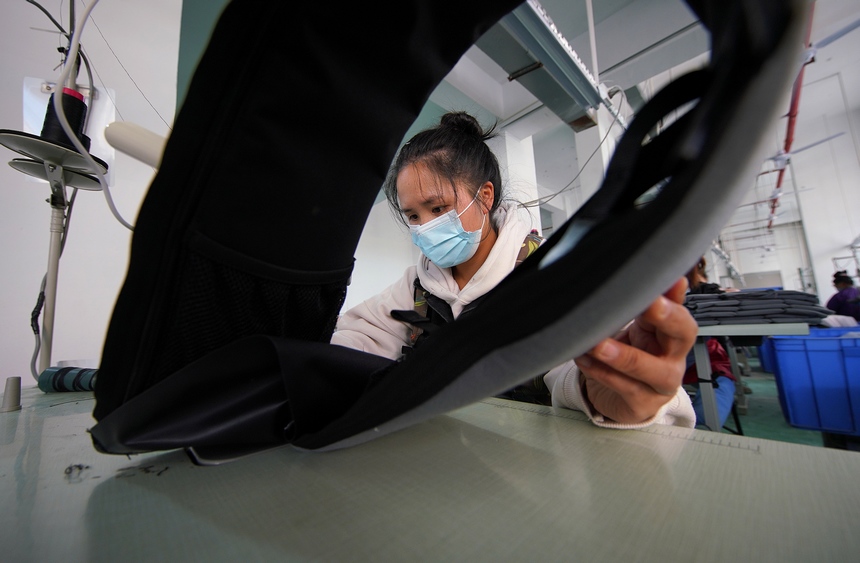 10月11日，工人在移民安置社區“幫扶車間”加工背包。