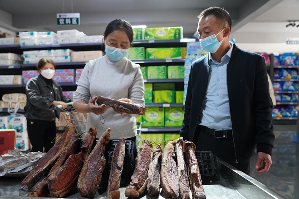 貴州省遵義市泥高鎮泥高社區居民在泥高鄉村振興服務站便民超市選購臘肉。