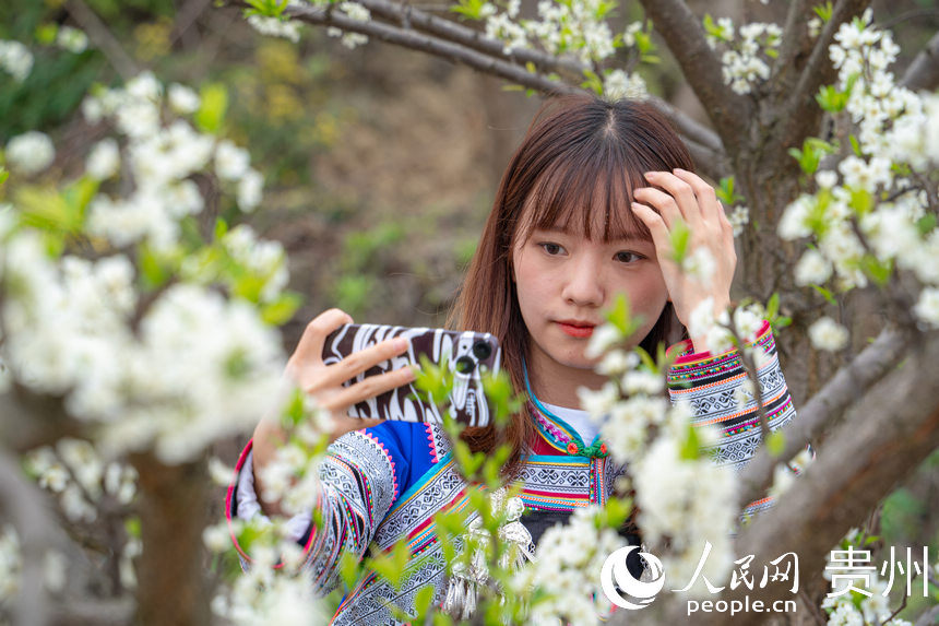 游客身著布依族服飾站在花叢里拍照。人民網 陽茜攝
