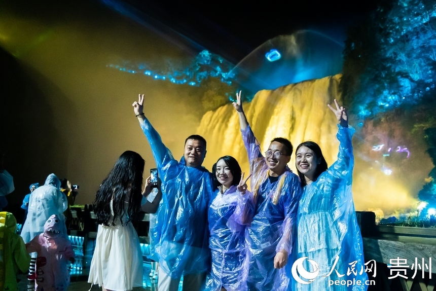 游客在夜間黃果樹前打卡拍照。人民網記者 涂敏攝