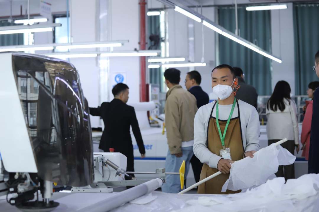  圖為工人操作機器裁剪布匹。