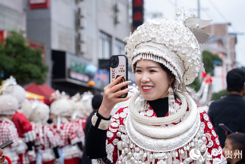 身著盛裝參加“蘆笙會”的苗族同胞為參加游演的同伴拍照。人民網記者 涂敏攝