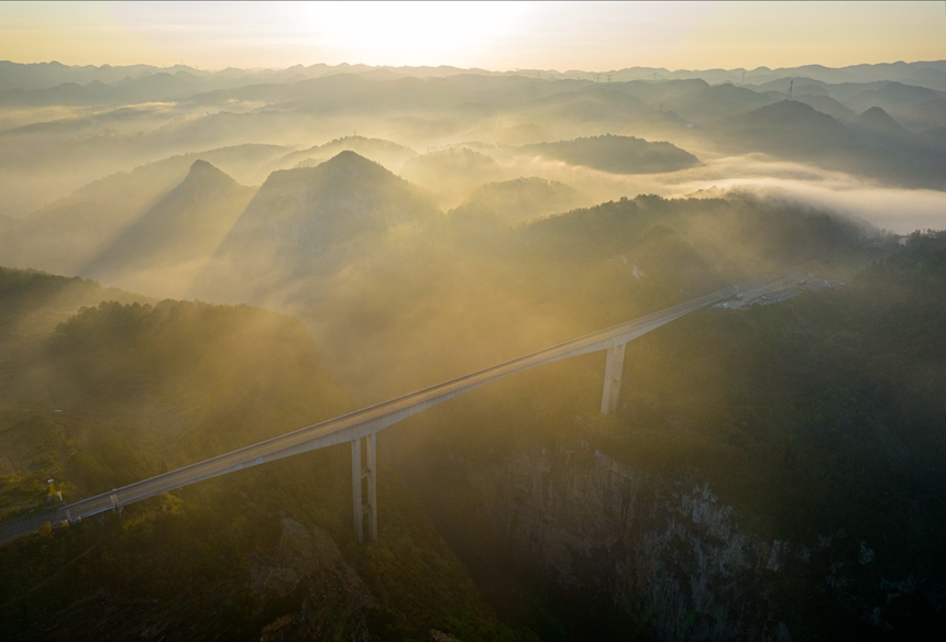 11月28日清晨，貴畢公路六廣河特大橋與云海、山川交相輝映，構成一幅壯美的交通畫卷。