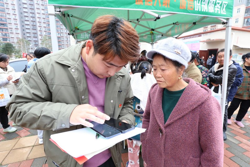 (3)2023年12月9日，清鎮市鄉愁社區云夢小鎮。圖為活動現場志愿者幫小區居民領取誠信消費券。（任芳靚 攝）.jpg