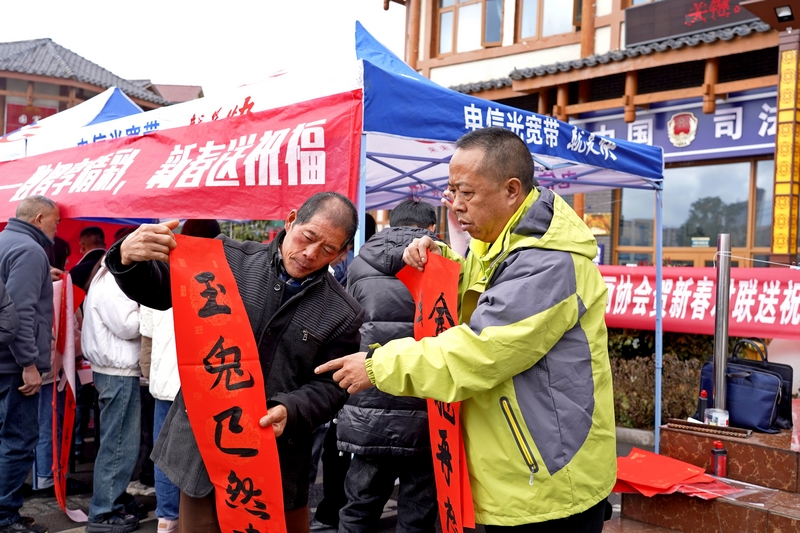 活動現場,電信公司工作人員給市民讀春聯。楊英攝