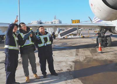 圖為邱超奕（中）在聽機務人員講解繞機檢查。