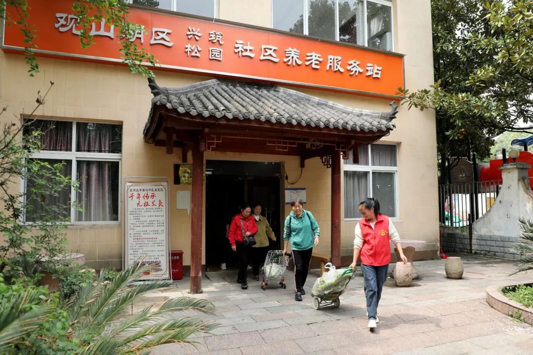 站點(diǎn)工作人員幫助老人送菜。