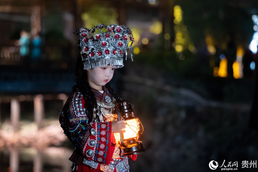 前來游玩的小朋友身著苗族特色服飾在景區內打卡拍照。人民網記者 涂敏 攝