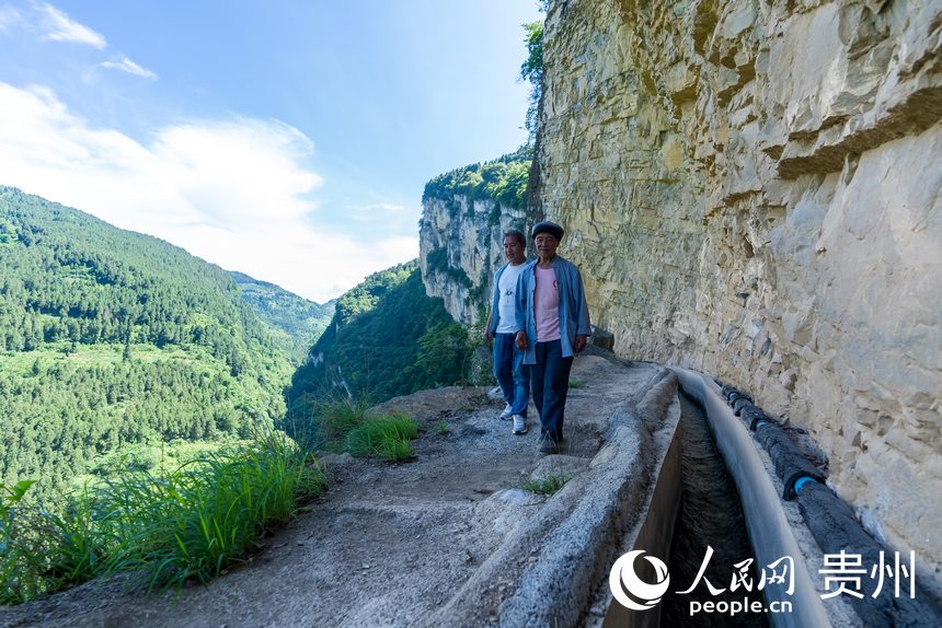 參與修建高流天渠的許光福老人和他的兒子許武君在巡查水渠。人民網(wǎng)記者 涂敏攝