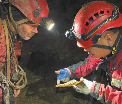 讓·波塔西(左)和中國專家在雙河洞一處支洞內觀察大熊貓化石。