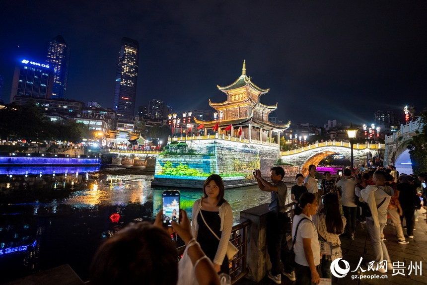 游客在甲秀樓激光投影前打卡拍照。人民網記者 涂敏攝