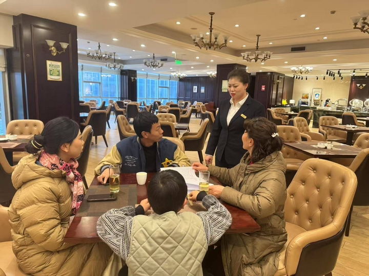 朗月國(guó)際酒店餐飲部經(jīng)理正在給顧客介紹年夜飯預(yù)訂優(yōu)惠情況 胡鳳至 攝.jpg