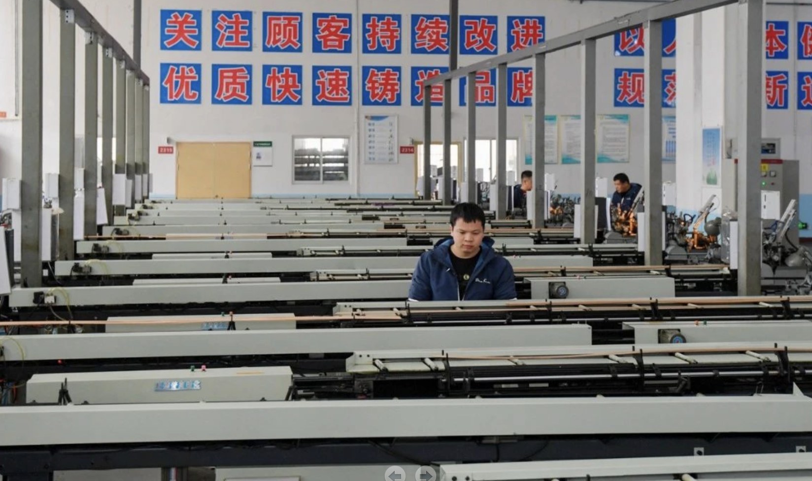 工人在生產(chǎn)線上查看智能生產(chǎn)設(shè)備運轉(zhuǎn)情況。