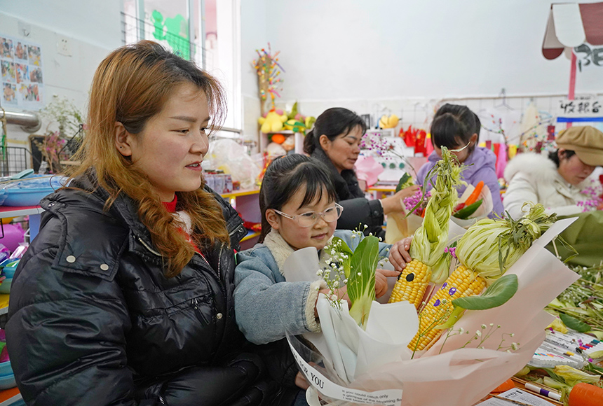 2025年3月6日,貴州省畢節市納雍縣龍場鎮中心幼兒園“溫情三八·感恩有您”活動現場,家長和孩子們一起做手工。 楊 英 攝