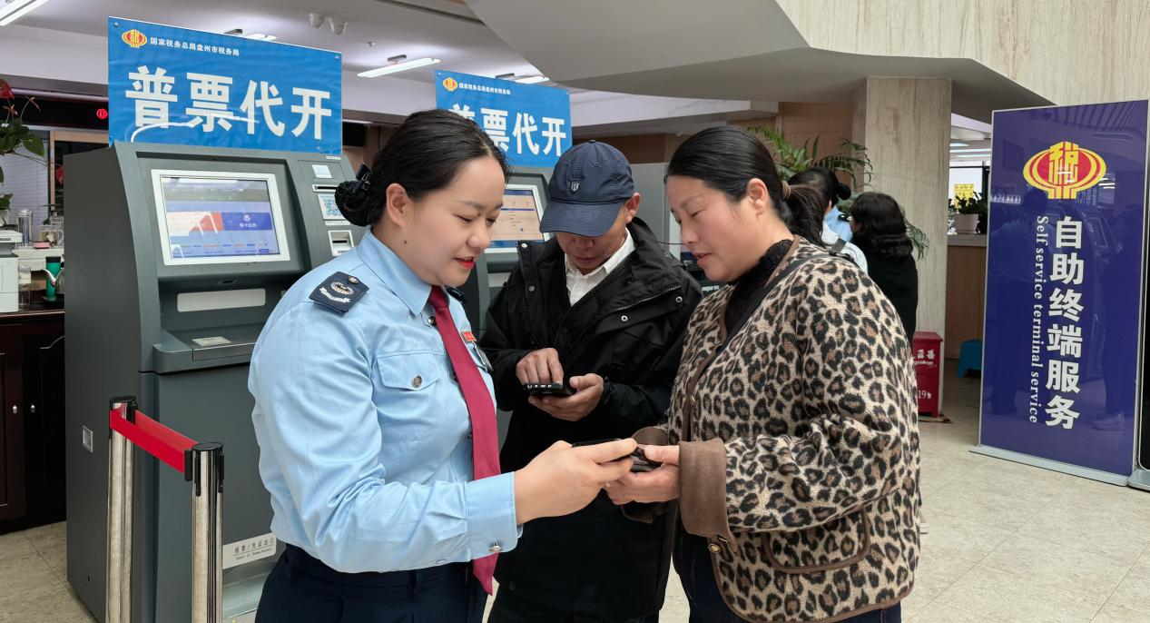 圖為 稅務(wù)干部輔導(dǎo)納稅人使用電子稅務(wù)局APP開具發(fā)票 張玉英/攝