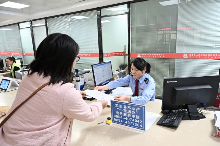 “一窗通辦”窗口工作人員為納稅人辦理不動產(chǎn)登記業(yè)務。