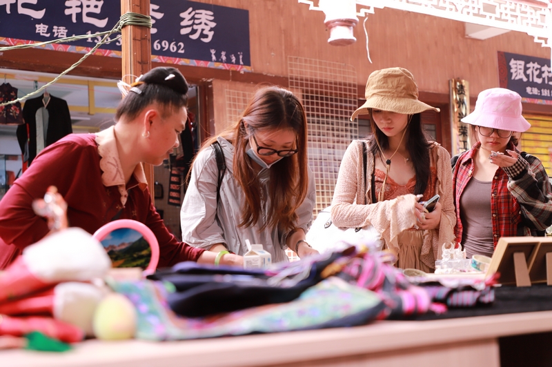 6月6日,在凱里市繡里淘非遺集市里,游客在挑選飾品。