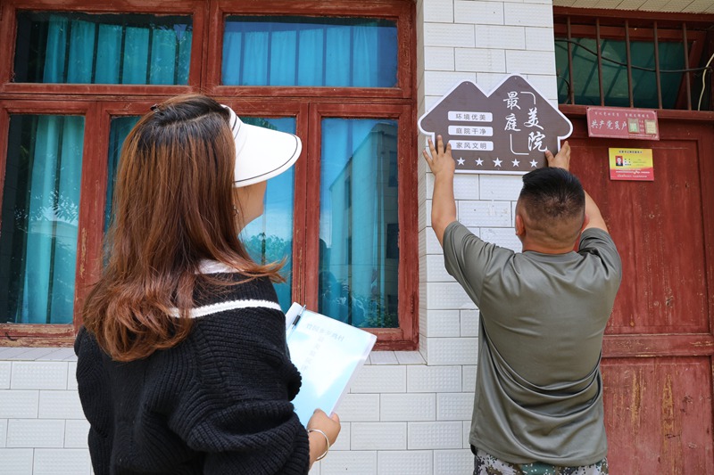 歹雞村村干部為村民張貼最美庭院牌子。