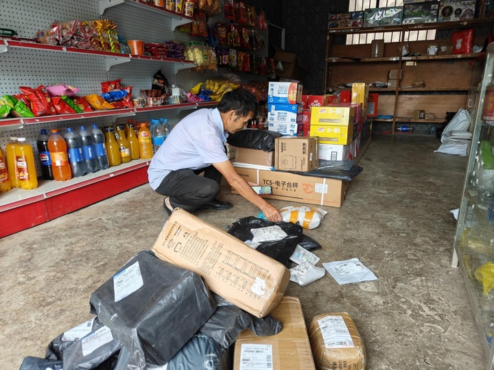 青山苗族鄉(xiāng)綠化村寄遞物流綜合服務(wù)站，店主正在整理快遞.jpg