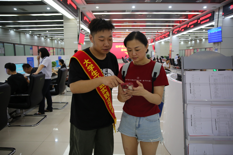 大學生志愿者輔導納稅人通過手機端電子稅務局開具發票。鄭婷攝