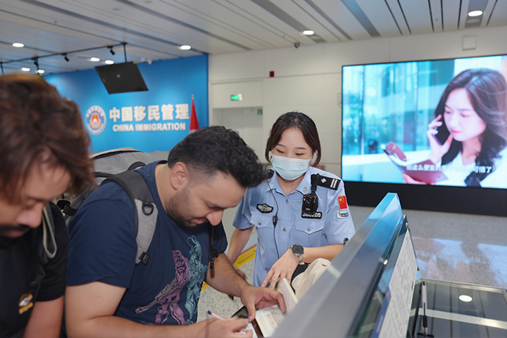 貴州邊檢總站執(zhí)勤三隊(duì)隊(duì)長(zhǎng)楊雨婕幫助入境外國(guó)籍旅客填寫入境卡。