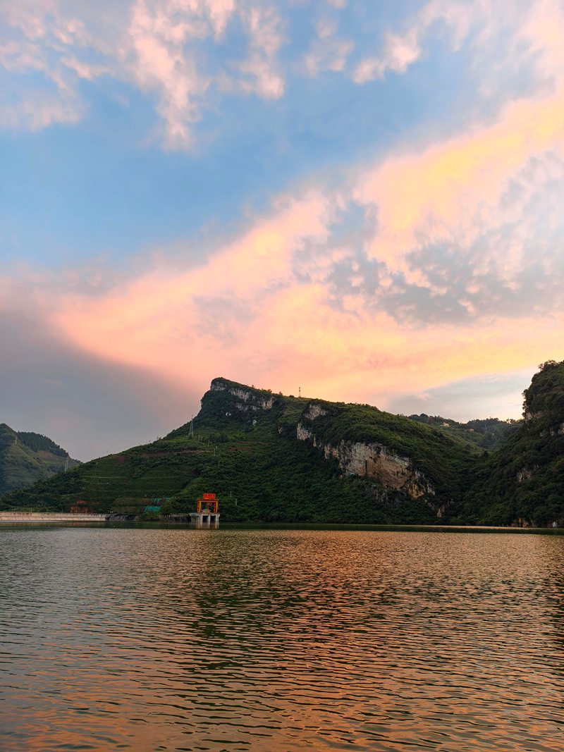 雨后的夾巖水庫空氣清新，落日余暉穿透云層，為天際染上橙紅、鎏金與淡紫的漸變色。張榮攝