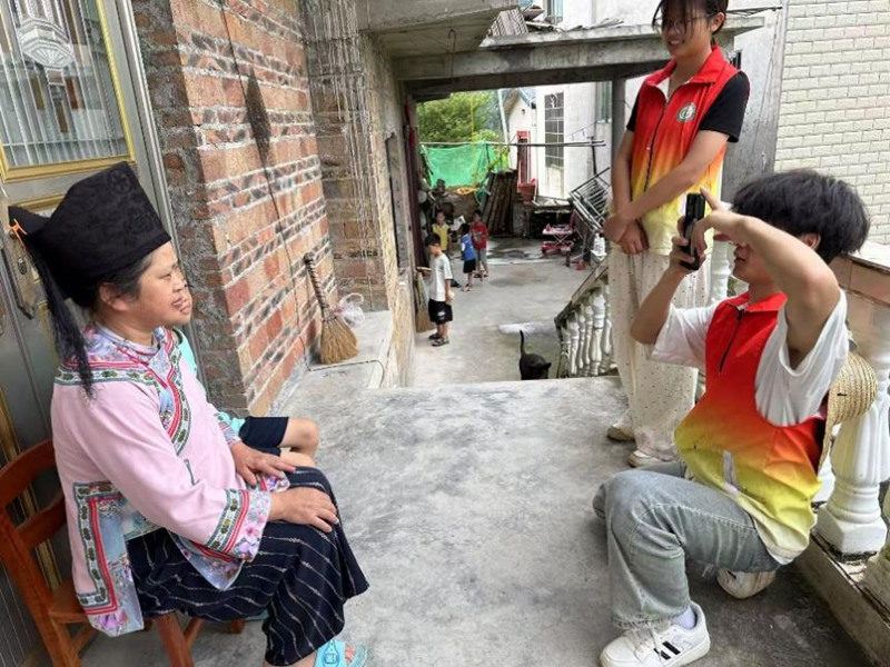 圖為志愿服務隊員調研完幫村民拍照。