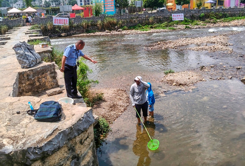 民警在河邊巡邏,提醒群眾不要下河玩水。