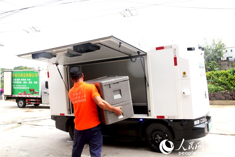 在貴陽家旺興食品有限公司，搬運人員正在給無人配送車裝貨。人民網記者 王秀芳攝