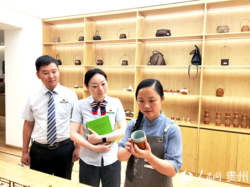 楊昌芹（左）給郵儲銀行赤水市支行工作人員展示“竹包瓷”茶具。人民網記者 王秀芳攝