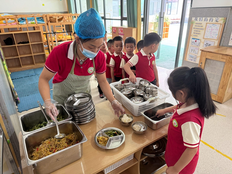幼兒園工作人員為孩子們分餐,餐食豐富多樣。謝永恒 攝.jpg