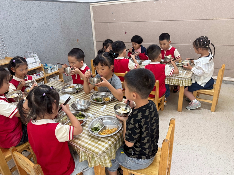 幼兒園孩子們?cè)诓妥狼伴_心用餐,氛圍溫馨。謝永恒 攝.jpg