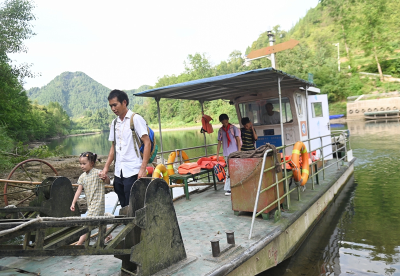 松桃苗族自治縣迓駕鎮教師任達兵帶著學生乘坐渡船回家。謝慧芳攝.JPG