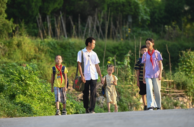 松桃苗族自治縣迓駕鎮教師任達兵帶著學生走在上學路上。謝慧芳攝 (2).JPG