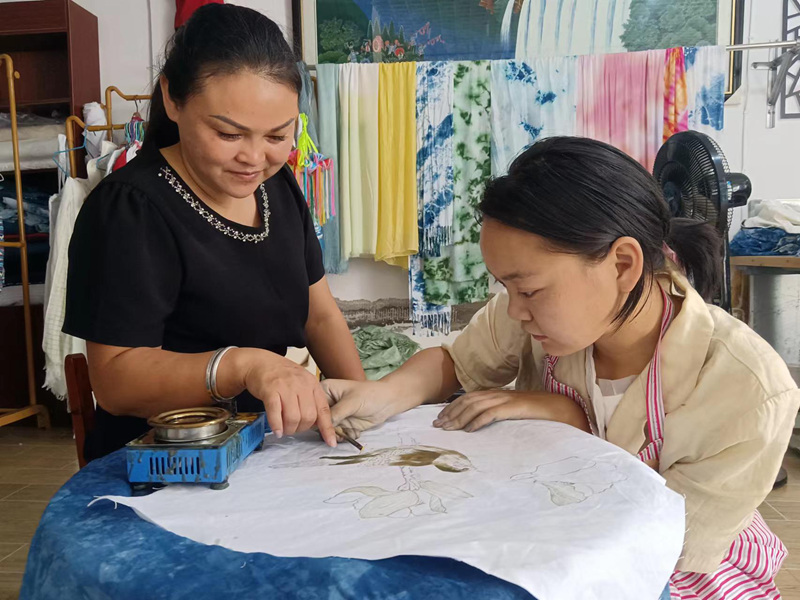 圖為梁海蘭指導梁玉芳畫蠟。