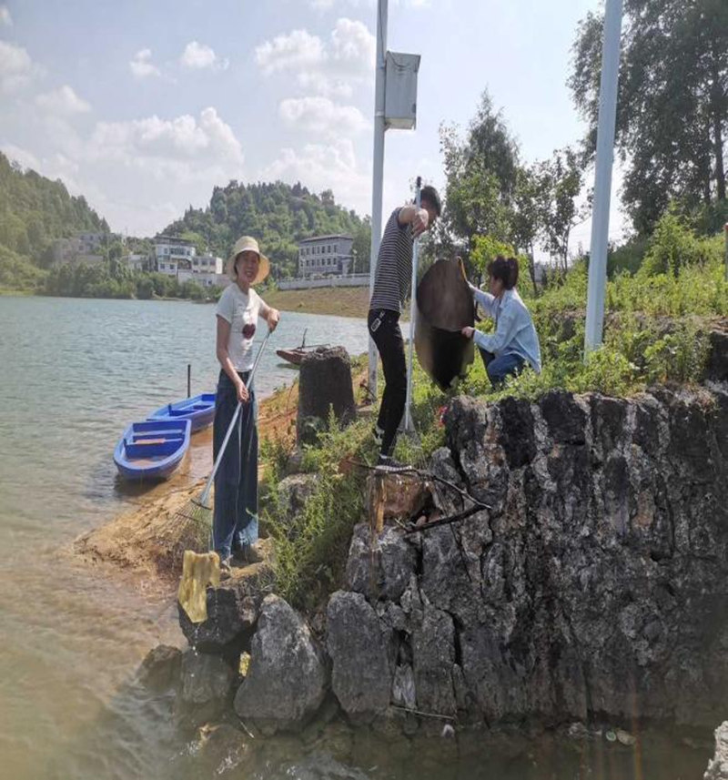 蘇流芳與駐村工作隊在湖面上清理垃圾。
