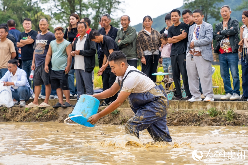摸魚(yú)比賽現(xiàn)場(chǎng)，參賽選手用水桶捉魚(yú)。人民網(wǎng)記者 涂敏攝