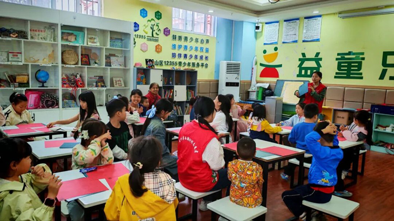 丹都街道旺家社區(qū)的志愿者正在給社區(qū)孩子們講解剪紙的技巧。