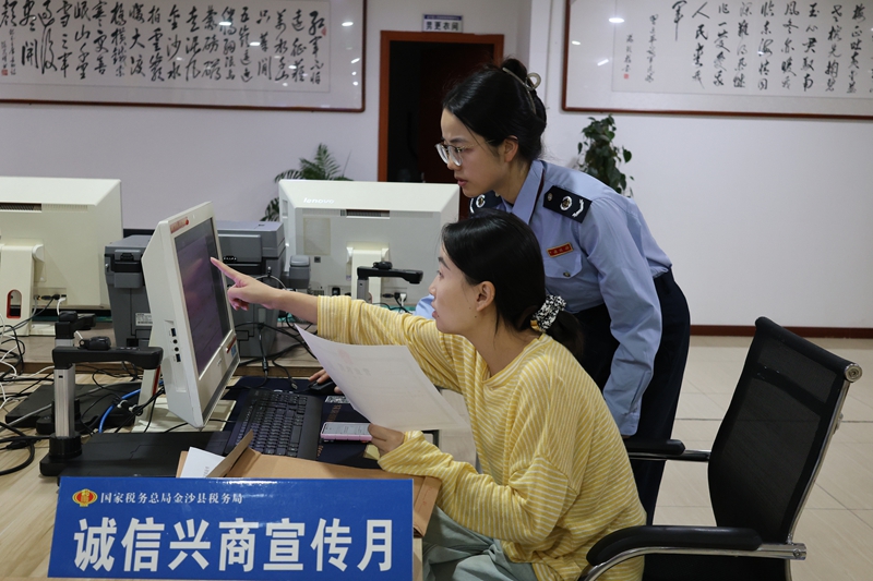 金沙縣稅務局辦稅服務廳內，稅務干部在向納稅人納稅信用評價標準與信用修復機制。助力誠信社會建設。顧拾金攝